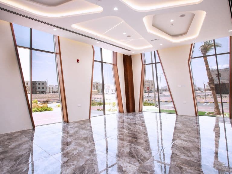 قاعة مضاءة طبيعيًا بنوافذ ممتدة من الأرض إلى السقف